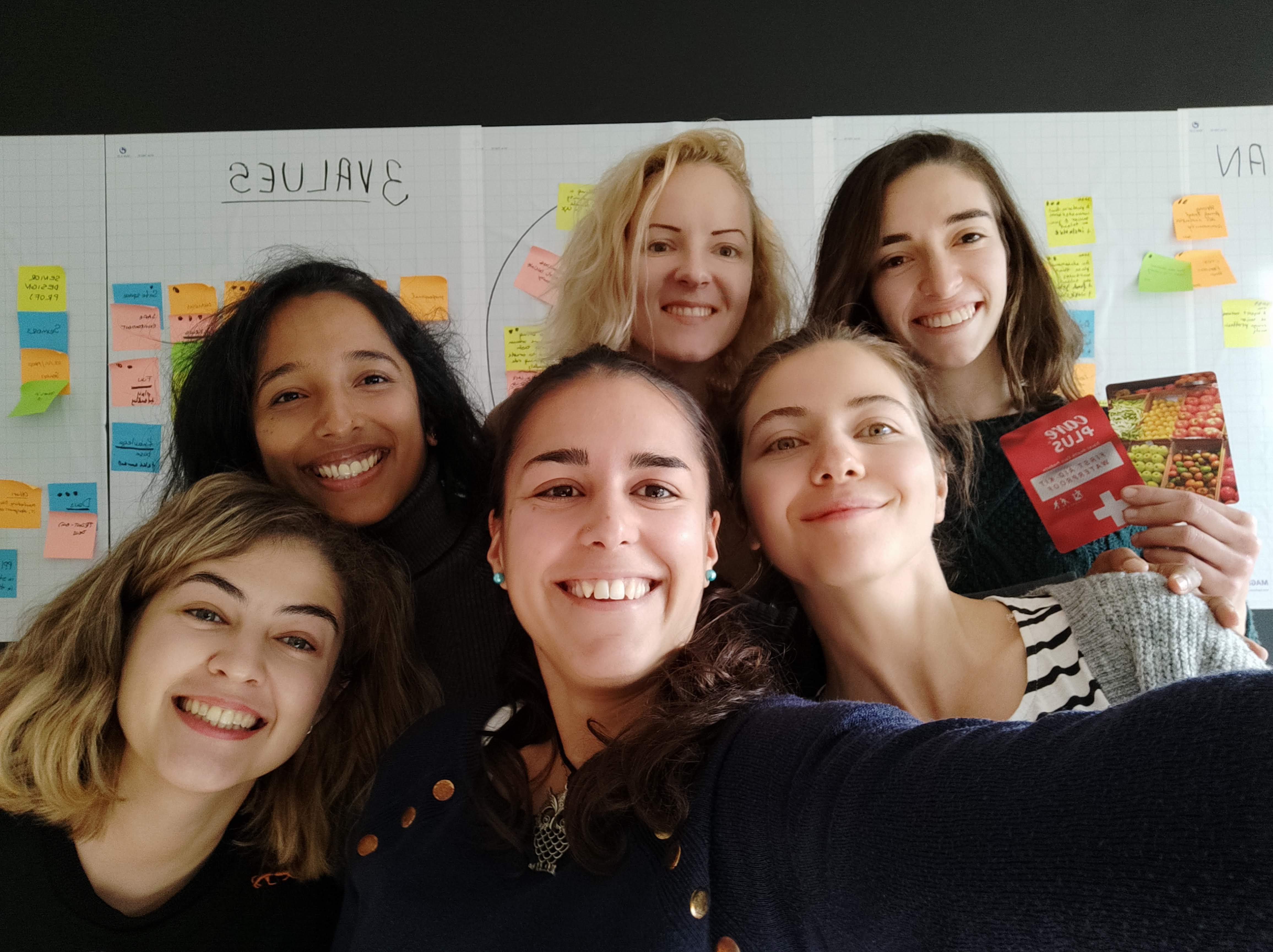 Ladies that UX Amsterdam organisers smiling together in front of a workshop wall